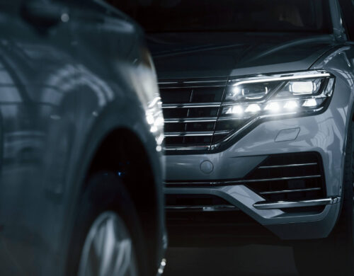 Powerful headlights. Particle view of modern luxury cars parked indoors at daytime.