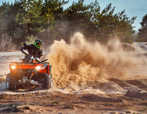 Teen riding ATV in sand dunes making a turn in the sand